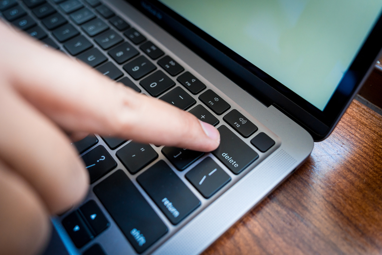 man pressing delete key to clean the junk from laptop